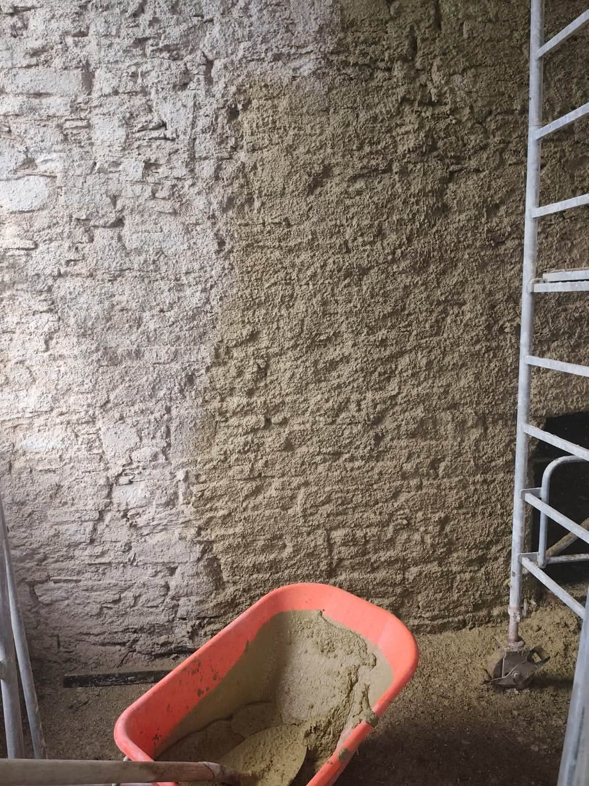 Freshly applied lime render across an exposed rubble stone wall
