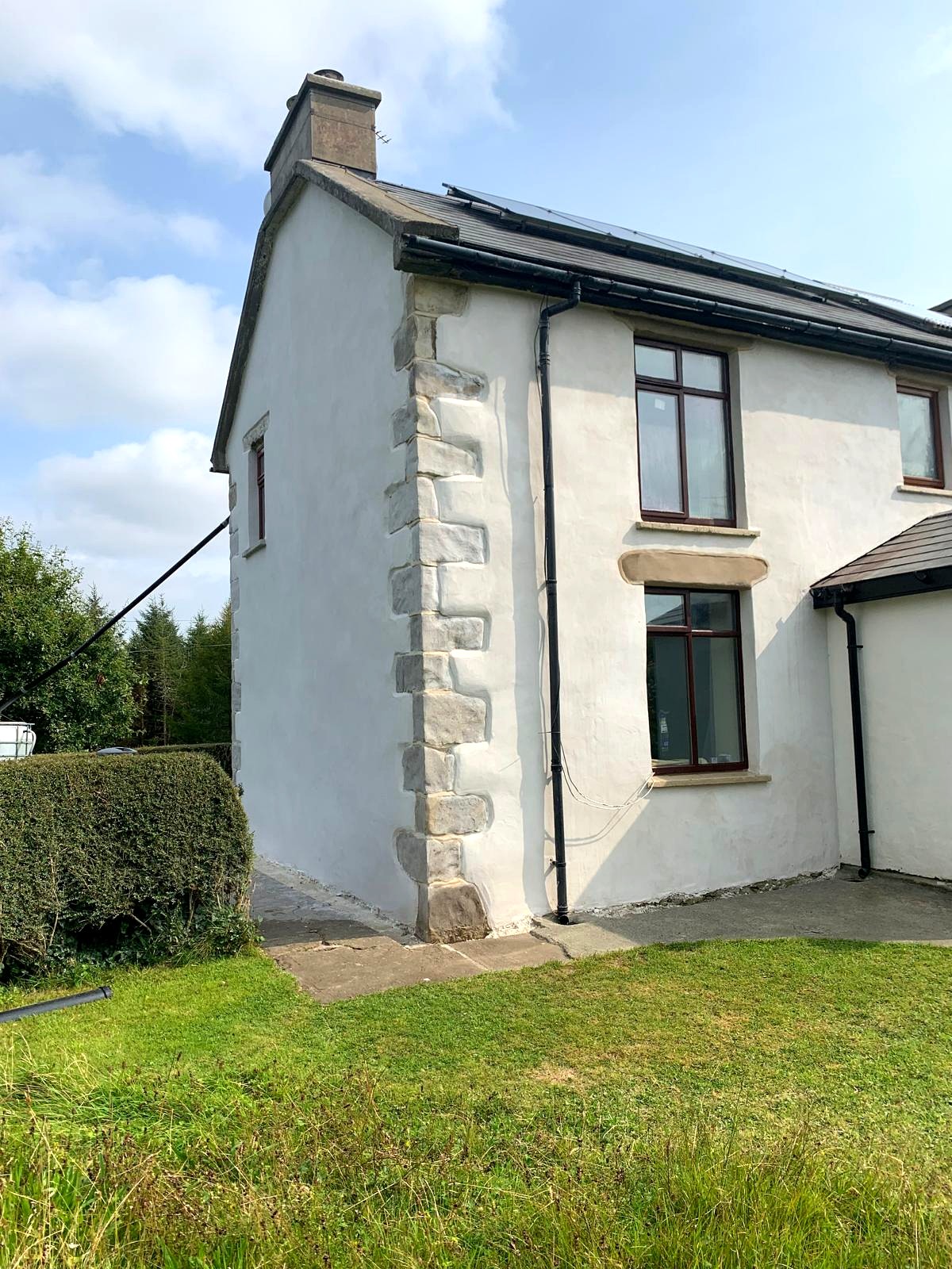 Gable corner of a farmhouse showing lime render feathered to exposed stone quoins