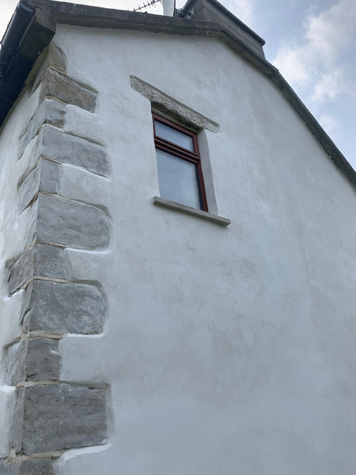 Corner of a traditional building with lime render and exposed stone quoins