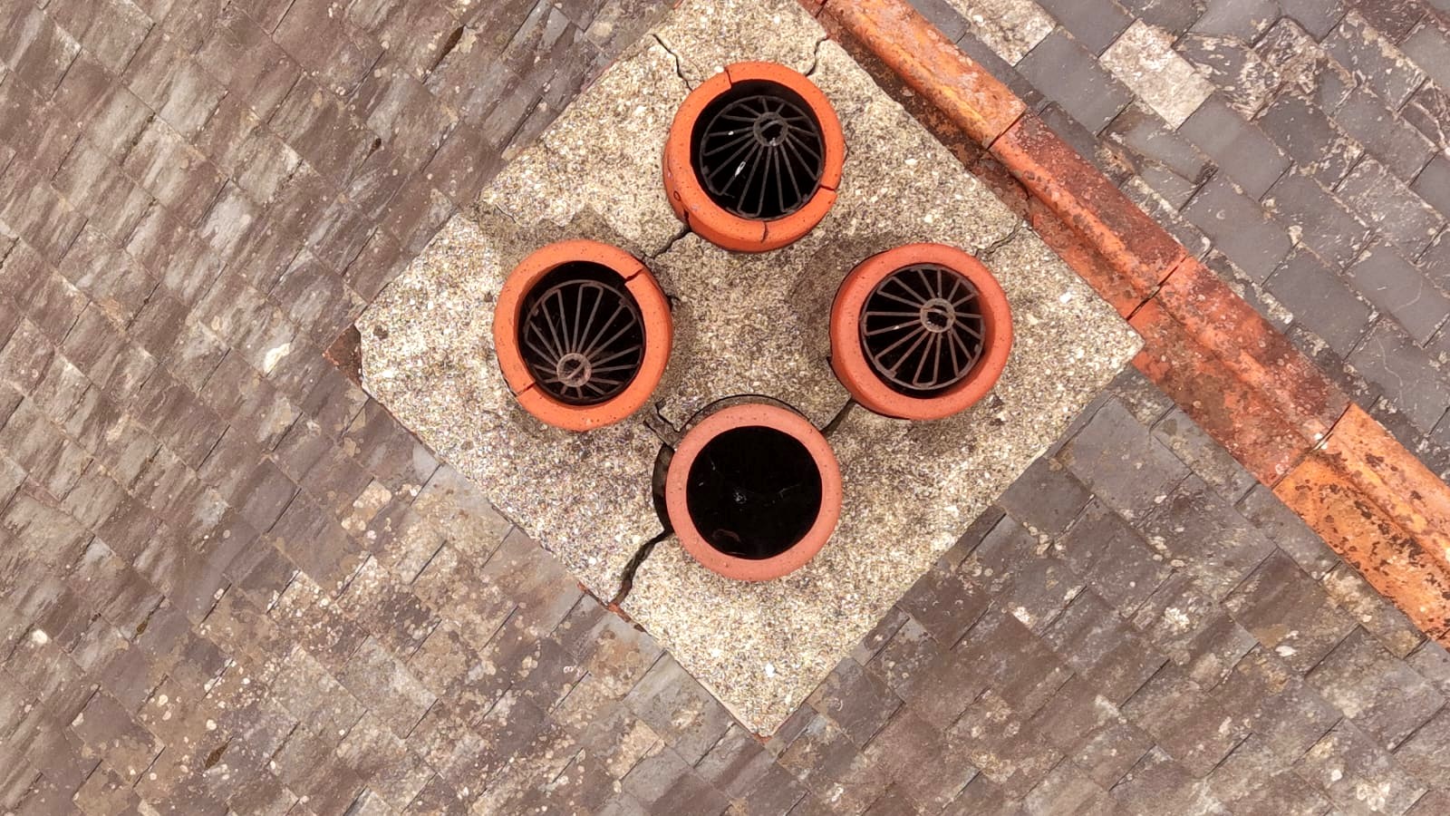 Chimney crown seen from directly above, with a crack through the mortar around four pots