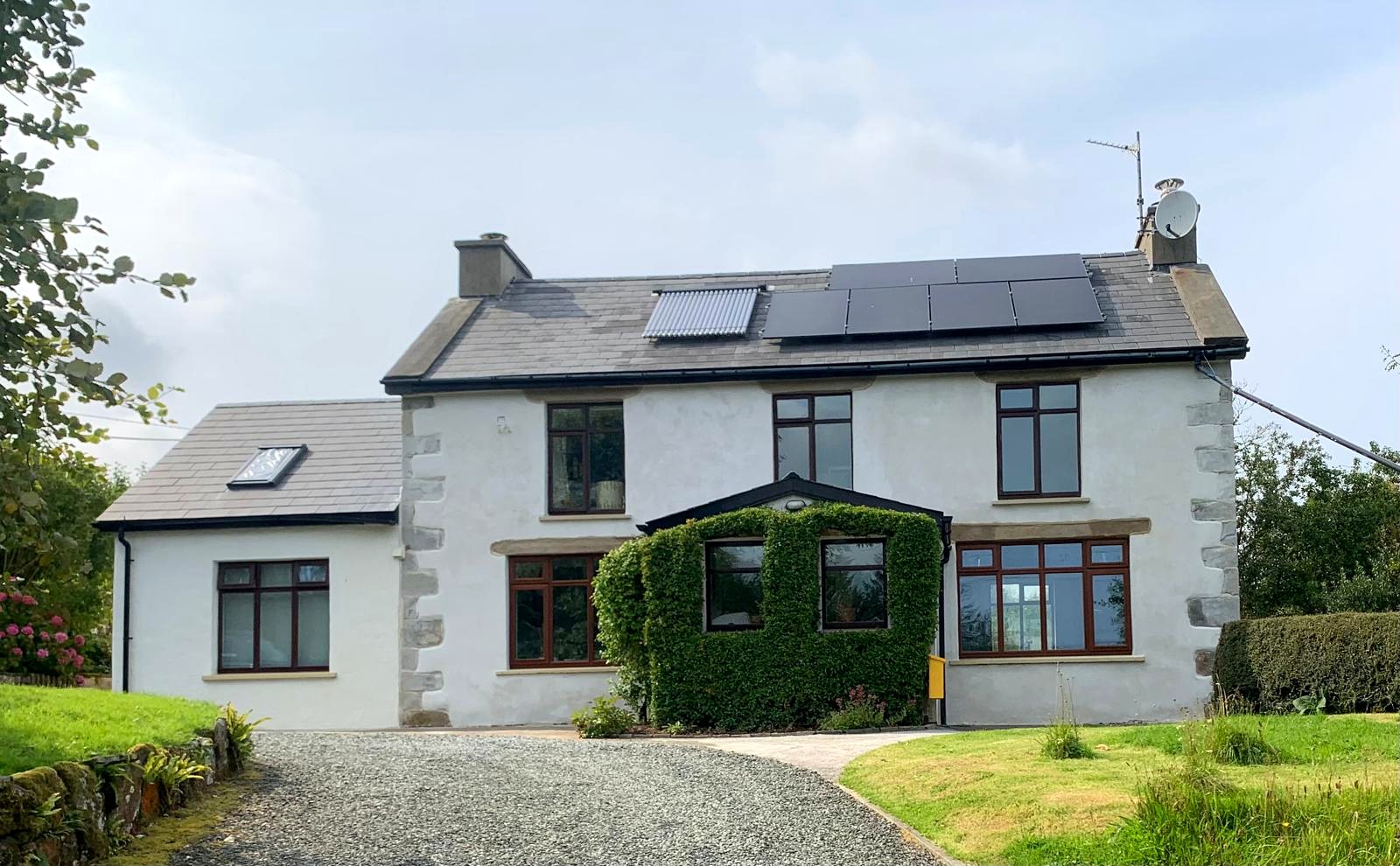 Two-storey Irish farmhouse finished in lime render with exposed stone quoins